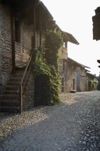 Scatto Fashion Street e ritratto ambientato nel borgo antico del Ricetto a Candelo: resa ottica vintage morbida e gestione della luce calda con ottiche modificate